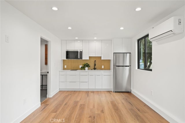 kitchen featuring a wall mounted air conditioner, modern cabinets, a sink, white cabinetry, and stainless steel appliances