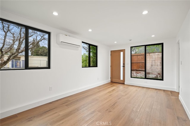 empty room with light wood-style flooring, recessed lighting, baseboards, and a wall mounted AC