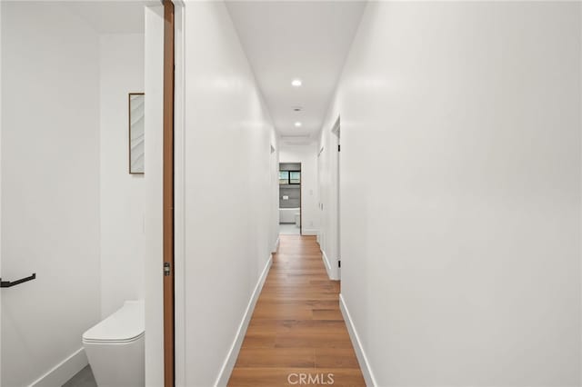 corridor featuring recessed lighting, baseboards, and light wood finished floors