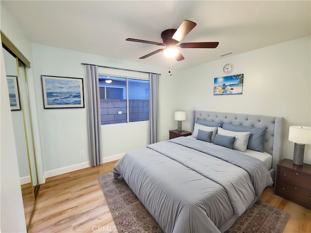 bedroom with light wood-type flooring, visible vents, baseboards, and ceiling fan