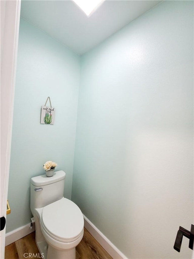 bathroom with baseboards, toilet, and wood finished floors