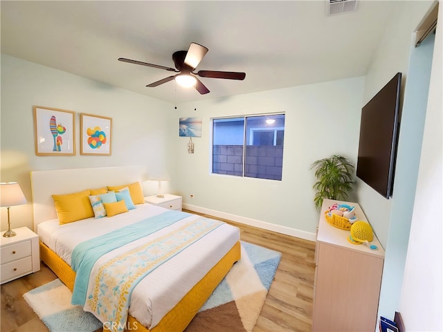 bedroom with ceiling fan, visible vents, baseboards, and wood finished floors