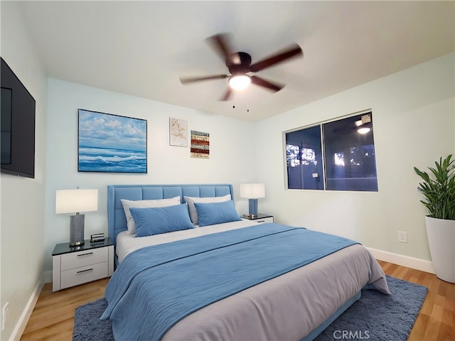 bedroom featuring light wood finished floors, ceiling fan, and baseboards