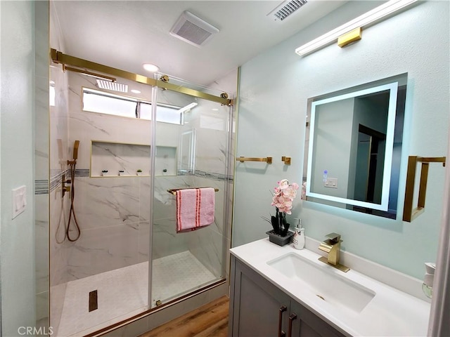 full bath with vanity, visible vents, and a marble finish shower