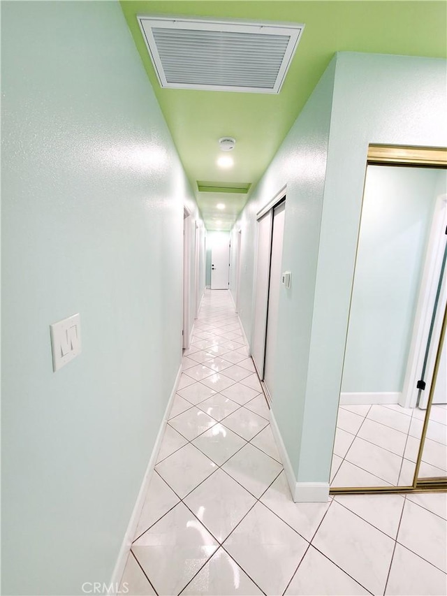 hallway with light tile patterned flooring, baseboards, and visible vents