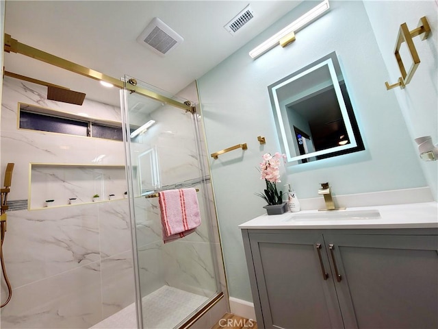 bathroom with a marble finish shower, visible vents, and vanity