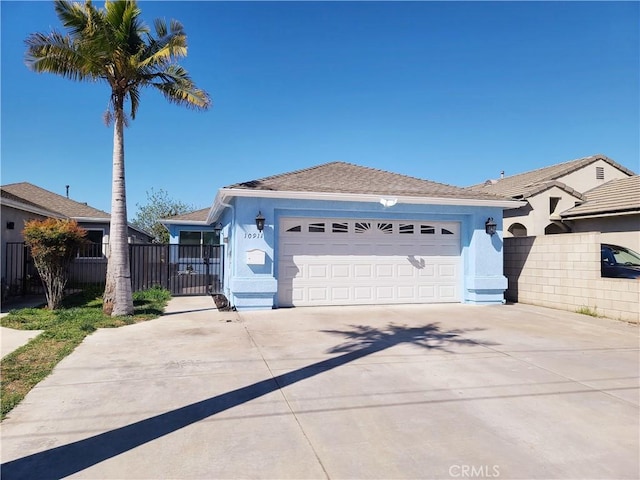 ranch-style home featuring an attached garage, fence, driveway, and stucco siding