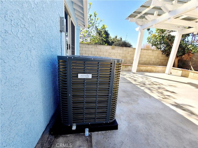 exterior details featuring stucco siding, cooling unit, and fence