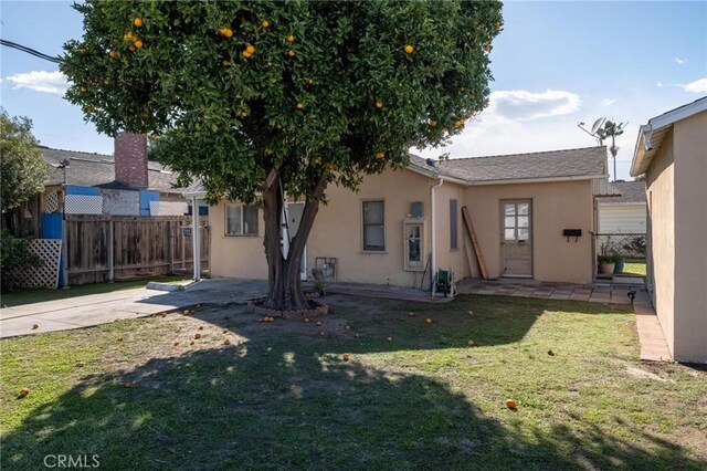 rear view of house with a patio area, a yard, fence, and stucco siding