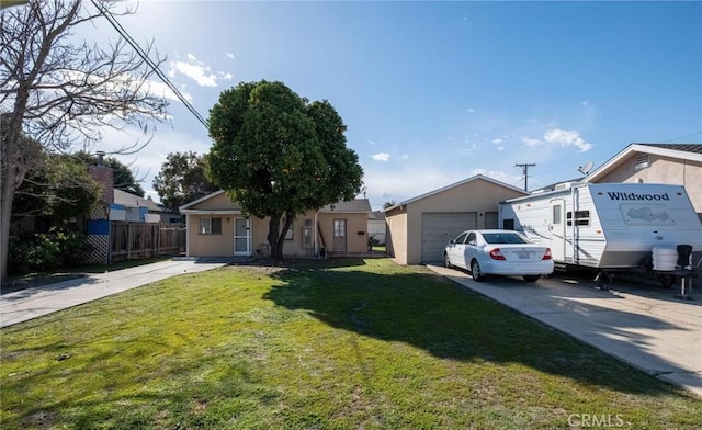 view of front of home featuring fence, driveway, a front lawn, an outdoor structure, and a garage