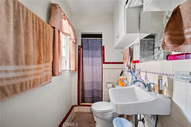 bathroom featuring a sink, a shower with curtain, tile walls, and toilet