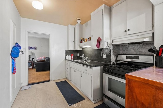 kitchen with light floors, a sink, white cabinets, under cabinet range hood, and stainless steel gas stove