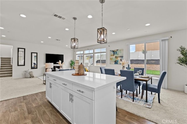 kitchen with open floor plan, a center island, white cabinetry, recessed lighting, and hanging light fixtures