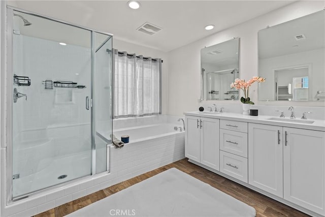 bathroom with a sink, visible vents, wood finished floors, and a stall shower