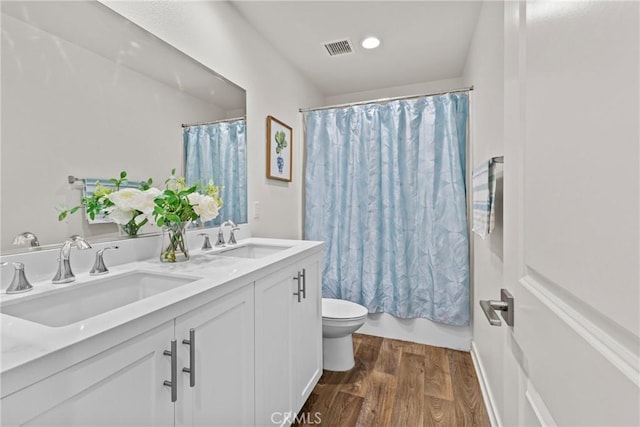 bathroom with wood finished floors, toilet, visible vents, and a sink