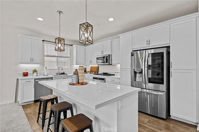 kitchen with a sink, appliances with stainless steel finishes, a center island, and white cabinetry