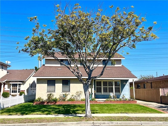 view of front facade featuring stucco siding, roof with shingles, a front yard, and fence