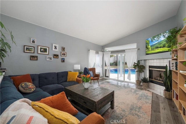 living area featuring lofted ceiling, wood finished floors, and a tile fireplace