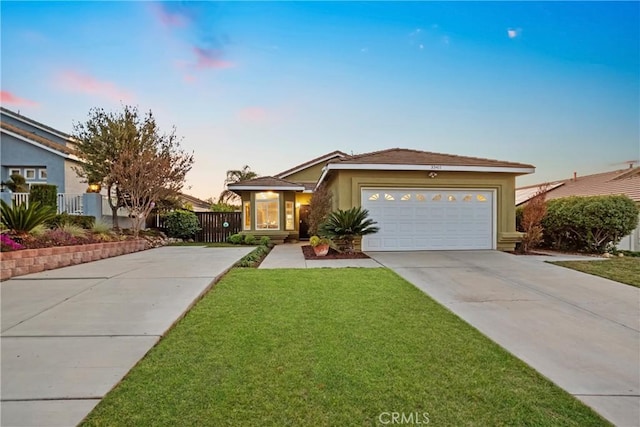 view of front of home featuring fence, concrete driveway, stucco siding, a lawn, and an attached garage