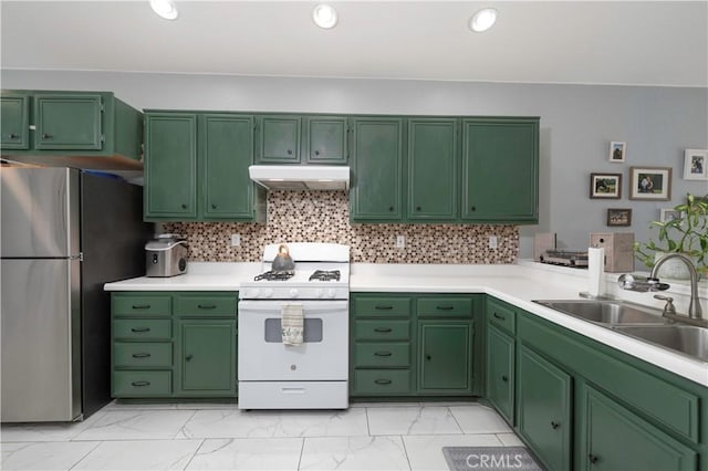 kitchen with marble finish floor, under cabinet range hood, a sink, gas range gas stove, and freestanding refrigerator