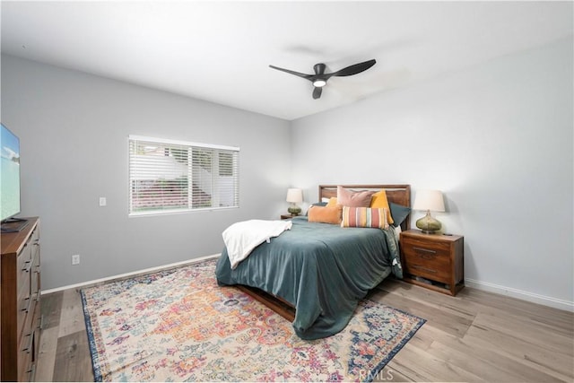 bedroom with a ceiling fan, baseboards, and light wood-type flooring