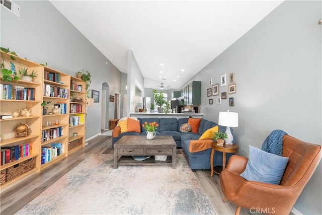 sitting room featuring visible vents, lofted ceiling, recessed lighting, wood finished floors, and arched walkways