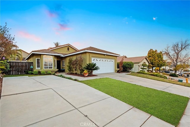 ranch-style home featuring stucco siding, a front lawn, driveway, fence, and an attached garage