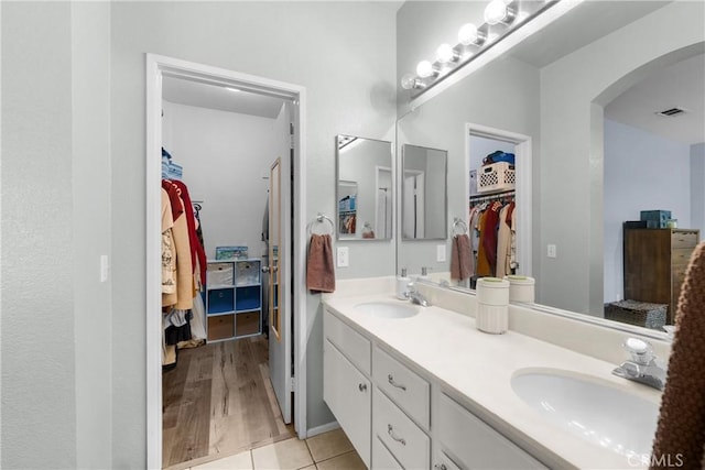 full bathroom with double vanity, a spacious closet, tile patterned floors, and a sink