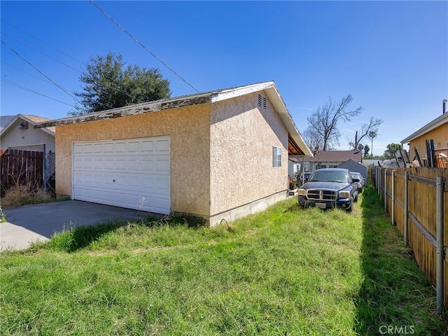 view of home's exterior featuring a yard, stucco siding, a garage, and fence