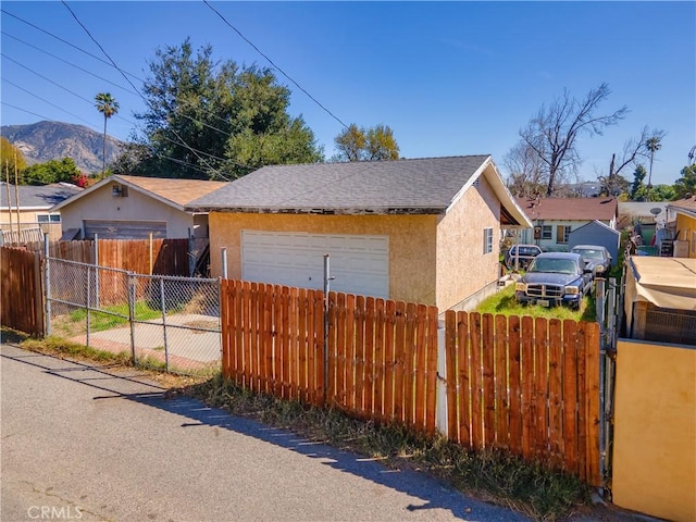 view of home's exterior featuring stucco siding, a fenced front yard, and a shingled roof