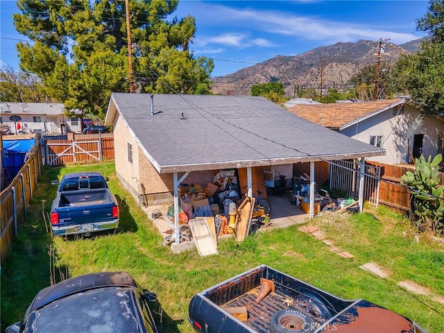 back of house featuring roof with shingles, a fenced backyard, a yard, a mountain view, and a patio