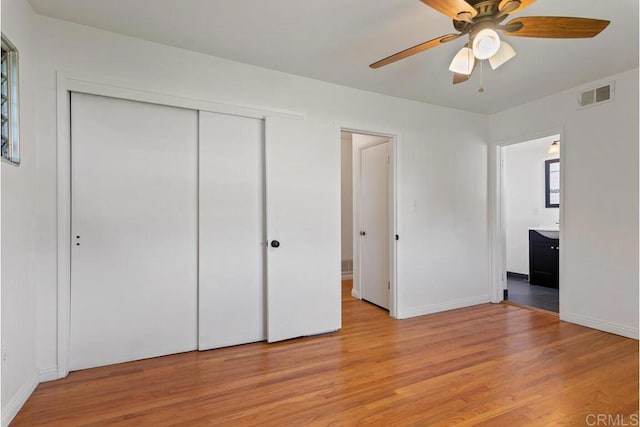 unfurnished bedroom with light wood-type flooring, visible vents, baseboards, and a closet