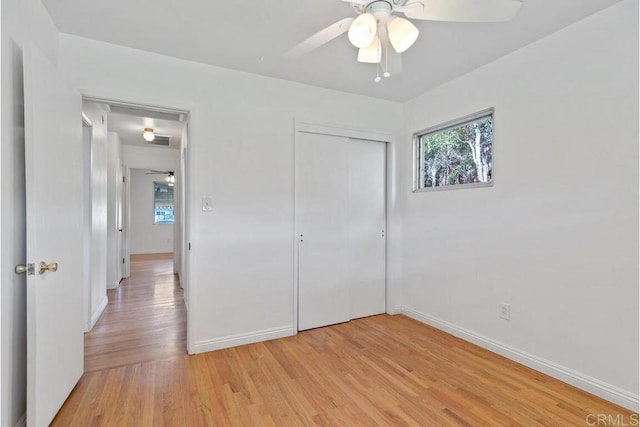 unfurnished bedroom featuring a closet, baseboards, ceiling fan, and light wood finished floors