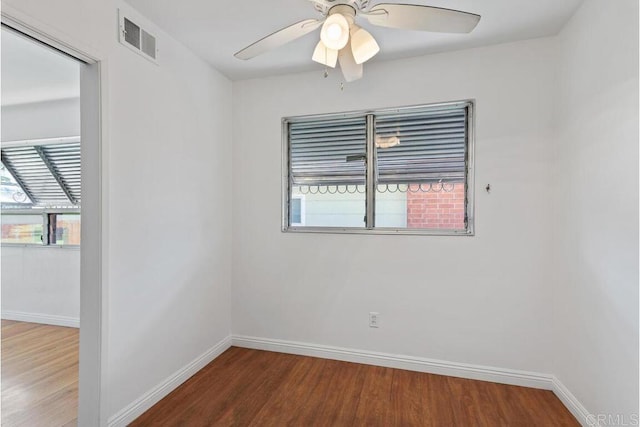 empty room with visible vents, a ceiling fan, baseboards, and wood finished floors