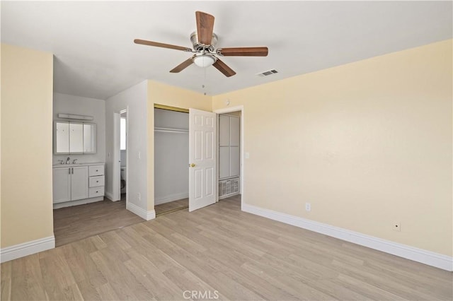 unfurnished bedroom with visible vents, baseboards, light wood-type flooring, a closet, and a sink