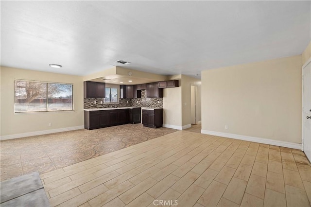 kitchen featuring tasteful backsplash, open floor plan, dark brown cabinets, and light countertops