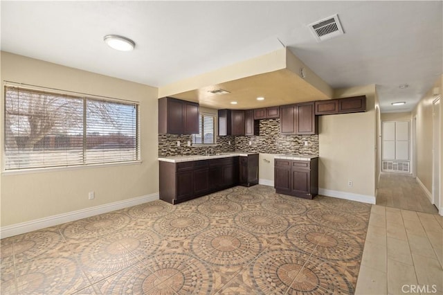 kitchen featuring visible vents, backsplash, dark brown cabinetry, and light countertops