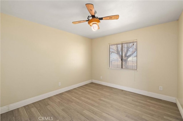 spare room featuring a ceiling fan, light wood-type flooring, and baseboards