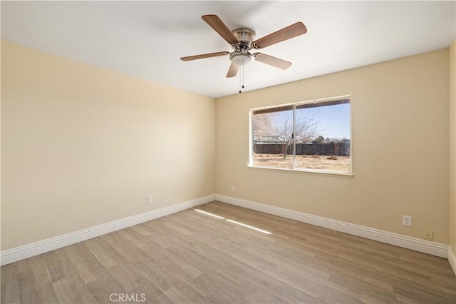 spare room featuring wood finished floors, baseboards, and ceiling fan