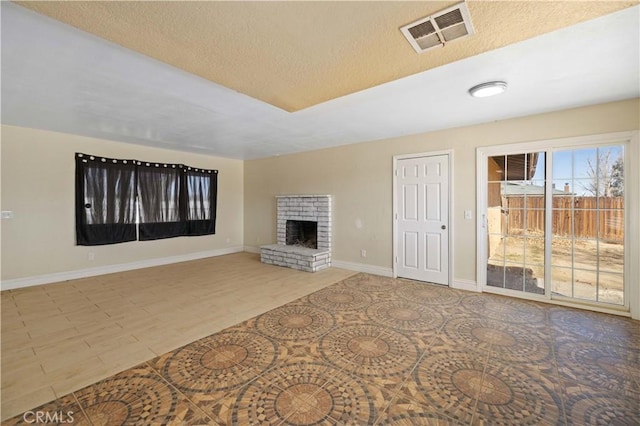 unfurnished living room with visible vents, a fireplace, a textured ceiling, and baseboards