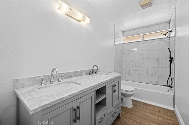 full bathroom featuring a textured ceiling, wood finished floors, visible vents, and a sink