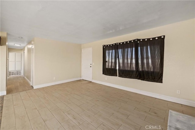 empty room with visible vents, baseboards, and wood finished floors