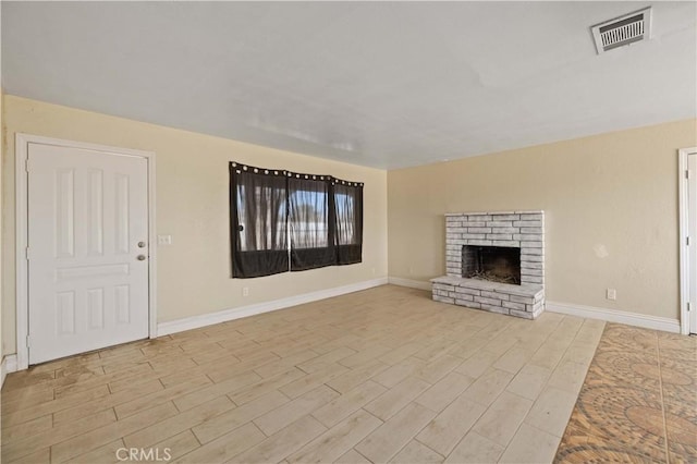 unfurnished living room featuring light wood-type flooring, visible vents, baseboards, and a brick fireplace