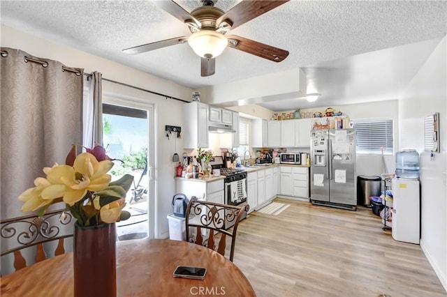 kitchen featuring a sink, white cabinets, under cabinet range hood, appliances with stainless steel finishes, and light wood-type flooring