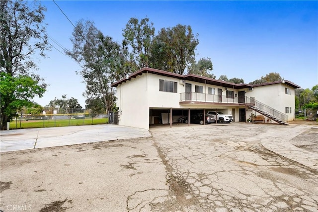 exterior space with stairway, fence, and a parking lot