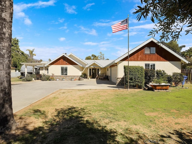 back of property with a lawn, a garage, concrete driveway, and a pergola
