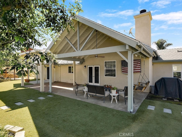 back of house with a patio, a chimney, stucco siding, a lawn, and french doors