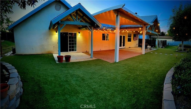 back of property featuring a patio, stucco siding, fence, and a lawn