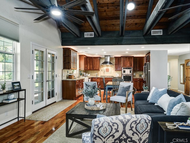 living area with visible vents, beam ceiling, and wood finished floors