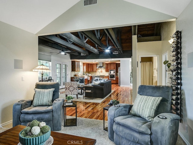 living room featuring high vaulted ceiling, visible vents, baseboards, ceiling fan, and light wood-type flooring